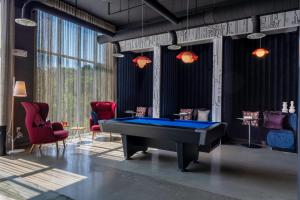 a pool table in a room with red chairs at Aloft Nashville Airport in Nashville