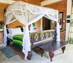 1 dormitorio con cama con dosel y mesa de madera en Villa Lyvie ayurvedic hotel, en Tangalle
