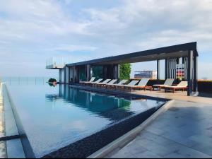 a swimming pool with chairs and a house at Pattaya Central & Infinity Pool in Pattaya Central