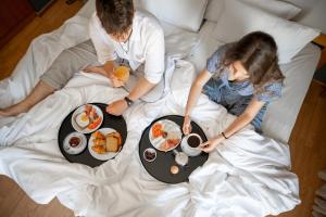 a group of three people laying in bed with breakfast at Olympic Hotel in Heraklio Town