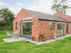 a brick cottage with a patio and a table at Curlew in Malpas