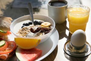 a bowl of cereal with fruit and a glass of orange juice at Kvibergs Vandrarhem - Hostel in Gothenburg