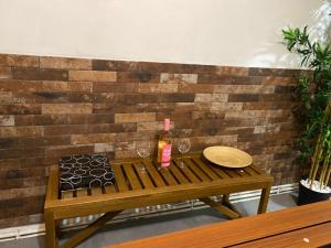 a wooden table with a bottle of wine next to a brick wall at Grand F3 Paris Stade de France & La Villette, 6 pers - Metro 7 in Aubervilliers