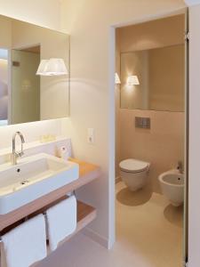a bathroom with a sink and a toilet at Falkensteiner Residences edelweiss in Katschberghöhe