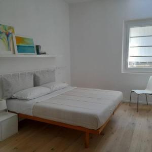 una camera da letto bianca con un letto e una sedia di Casacciuga, luminosa e centrale casa con giardino a Pesaro