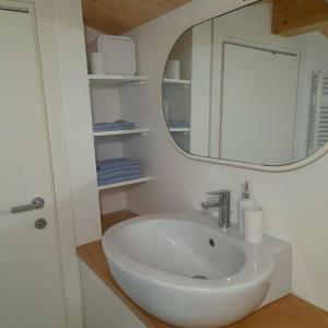 W łazience znajduje się biała umywalka i lustro. w obiekcie Casacciuga, luminosa e centrale casa con giardino w mieście Pesaro