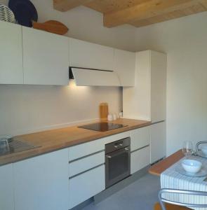 uma cozinha com armários brancos e um forno com placa de fogão em Casacciuga, luminosa e centrale casa con giardino em Pesaro