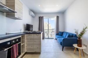 eine Küche und ein Wohnzimmer mit einem blauen Sofa in der Unterkunft Serafina's Apartment 5 min walk from St Julians in San Ġwann
