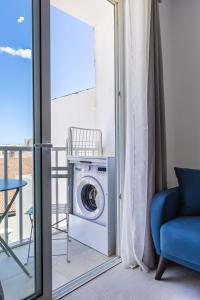 eine Waschmaschine auf einem Balkon mit einem blauen Stuhl in der Unterkunft Serafina's Apartment 5 min walk from St Julians in San Ġwann