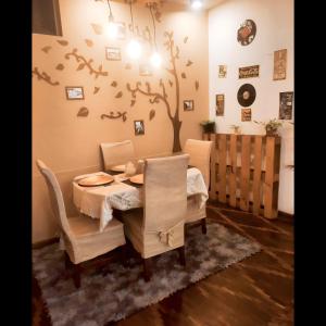 ein Esszimmer mit einem Tisch und Stühlen sowie einem Baum an der Wand in der Unterkunft Irania House - Hermoso departamento con estilo diferente in Loja