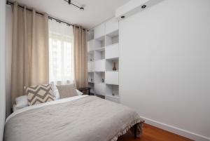 a white bedroom with a bed and a window at Arena Ursynów Luxury Apartment in Warsaw