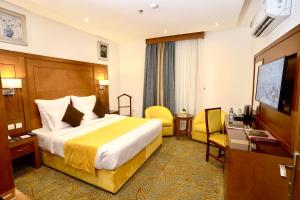 um quarto de hotel com uma cama e uma televisão de ecrã plano em Rose Jeddah Hotel em Jidá