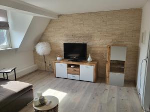 a living room with a tv and a brick wall at Ferienwohnung im Rebstock Nr.1 in Bahlingen
