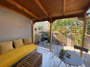 ein Wohnzimmer mit einem gelben Sofa und einem Tisch in der Unterkunft NEW! Flower Patio House 2 BDR - BBQ - Wash machine in Lávrio