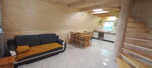 ein Zimmer mit einem Sofa und einem Tisch sowie einer Küche in der Unterkunft Bieszczadzkie domki in Bukowiec