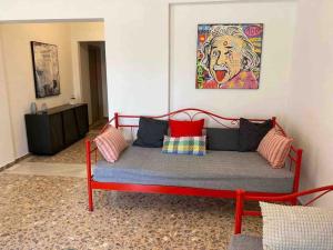 un sofá rojo con almohadas en la sala de estar en NEW! Flower Patio House 2 BDR - BBQ - Wash machine en Lávrion