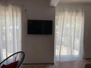 a living room with white curtains and a flat screen tv at NEW! Flower Patio House 2 BDR - BBQ - Wash machine in Lávrion