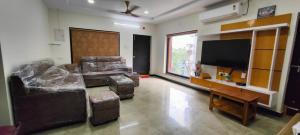 a living room with a couch and a tv at Magnolia Villa Luxury 3 Bedroom Apartments in Visakhapatnam