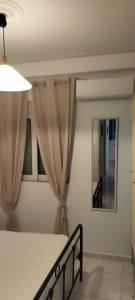 1 dormitorio con 1 cama con cortinas y espejo en Periklis House en Ixia