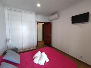 um quarto com uma cama vermelha e uma televisão na parede em 1 Torre Sol 2 - Casas & Papeis em Armação de Pêra