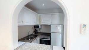 a kitchen with white cabinets and a stainless steel refrigerator at Apartamento en el campo de golf Son Parc, Menorca in Son Parc