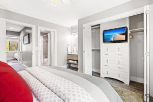 a white bedroom with a bed and a tv at Condo Serenity in Charleston