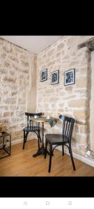 two chairs and a table in a room with a stone wall at IMHOST - Amazing architect studio Père Lachaise in Paris
