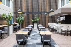 ein Restaurant mit Tischen und Stühlen und eine Bar in der Unterkunft Holiday Inn Express The Hague - Parliament, an IHG Hotel in Den Haag