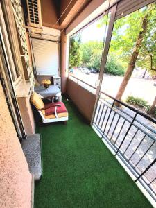 a balcony with green flooring and a large window at Center 1 Podgorica in Podgorica