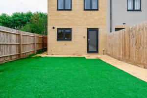 a backyard with a green lawn in front of a house at Modern, Spacious House with Free Parking & Garden in Swindon