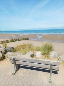 a bench sitting on the beach near the ocean at Ô de Vents - à 30m de la plage in Sangatte