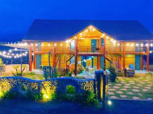 une grande maison en bois avec des lumières devant elle dans l'établissement Săn Mây Coffee and Homestay Măng Đen, à Kon Von Kla