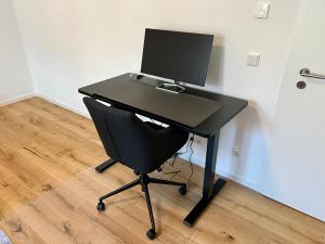 a black desk with a computer on top of it at Workplace Apt/27inch Screen for 2 or 4/Kitchen in Offenbach