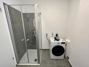 a bathroom with a shower and a washing machine at Workplace Apt/27inch Screen for 2 or 4/Kitchen in Offenbach
