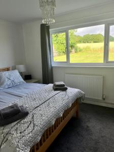 a bedroom with a bed and a large window at Cosy bungalow with views, walks, garden & parking. in Worcester