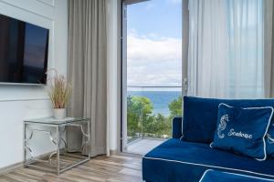 een woonkamer met een blauwe bank en een glazen schuifdeur bij Your Holidays Promenada Gwiazd 14 in Międzyzdroje