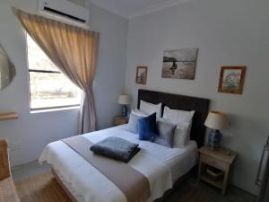 a bedroom with a large white bed with blue pillows at Matjesfontein Estate Keurbooms Chalet in Plettenberg Bay