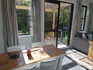 una sala de estar con mesa y sillas y una habitación con ventanas en Matjesfontein Estate Keurbooms Chalet, en Plettenberg Bay