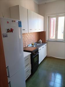 a kitchen with white cabinets and a white refrigerator at Appartamento Achiazza Scala dei Turchi in Realmonte