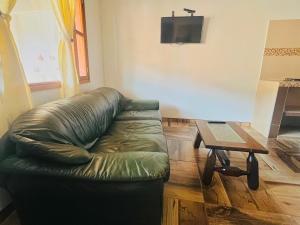a living room with a green leather couch and a table at Villa villa in Villa de Leyva