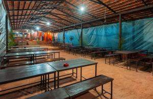 a group of tables in a building with blue tarp at Treebo Trend Rock Valley in Ponda