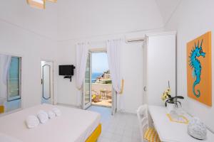 een witte kamer met 2 bedden en een balkon bij CASA DAMA in Positano