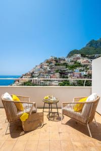 einen Balkon mit Stühlen und einem Tisch mit Aussicht in der Unterkunft CASA DAMA in Positano