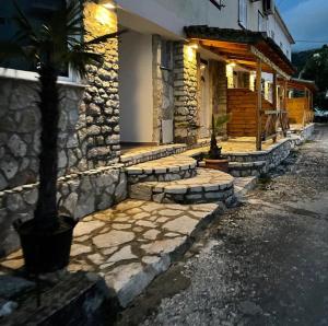a stone house with a palm tree in front of it at Jona Rooms in Himare