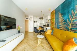 uma sala de estar com um sofá amarelo e uma mesa em Mia Mare Premium Apartment by Perłowa Przystań Rent em Kolobrzeg
