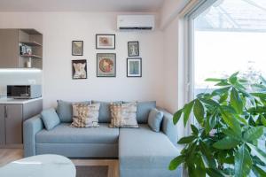 a living room with a blue couch and a plant at Daphne by halu! : Downtown family penthouse in Thessaloniki