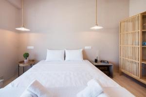 una camera da letto con un grande letto bianco e due tavoli di Daphne by halu! : Downtown family penthouse a Salonicco