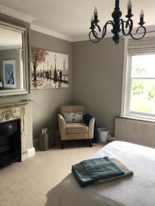 a bedroom with a bed and a chair and a fireplace at Balcarres, Rodborough Avenue in Stroud