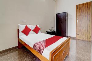 a bedroom with a bed with red pillows at OYO Flagship V A S Lodge in Punjai Puliyampatti