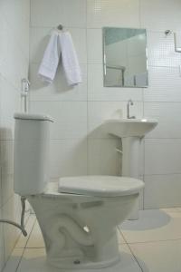 a white bathroom with a toilet and a sink at Clip d´Oro Hotel in Camaçari